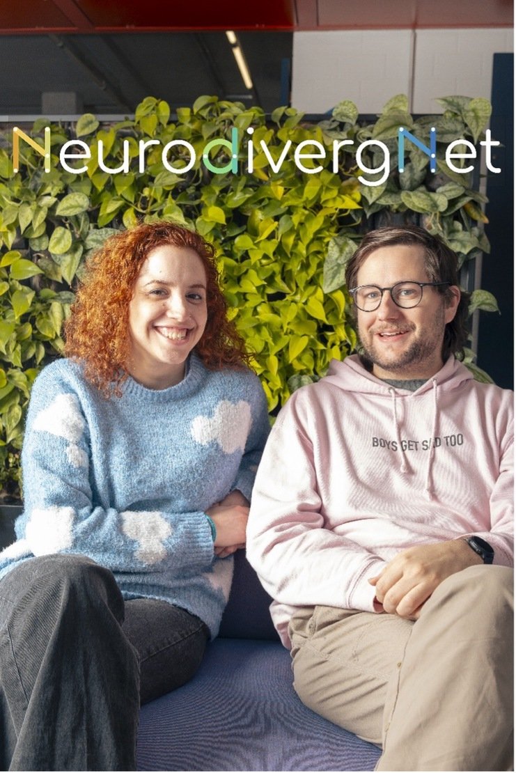 Two people smile on a sofa in front of a green plant wall, under the NeurodivergNet logo