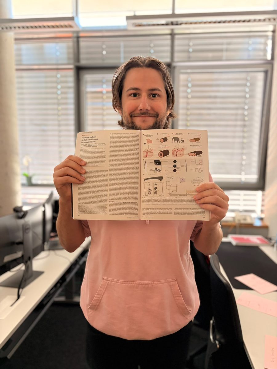 A researcher holds open a printed issue of Science at the elephant whisker paper